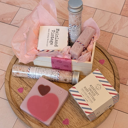 Collection of bath products including soaps and bath salts on a wooden tray.