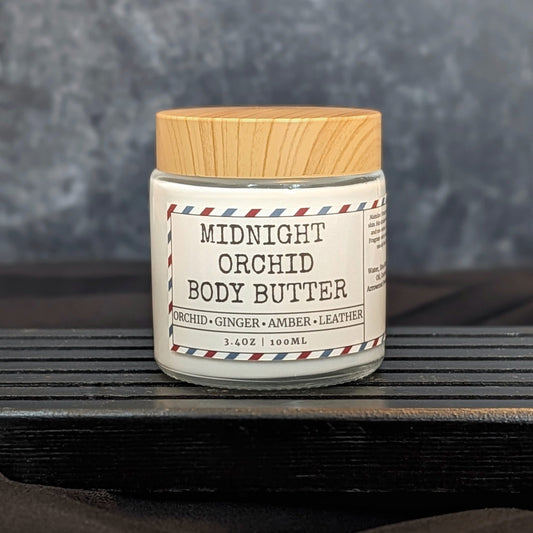 Jar of Midnight Orchid Body Butter on a wooden surface with a gray background